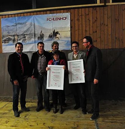 Sei persone in posa con attestati in mano, in un ambiente interno con una grande immagine di un paesaggio sullo sfondo. Atmosfera di celebrazione.
