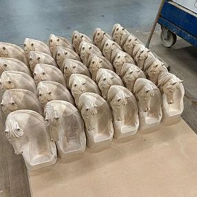 A collection of identical ceramic molds shaped like animal heads arranged in rows on a wooden surface, possibly in a workshop or industrial setting.