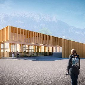 Moderne Holzarchitektur eines Gebäudes vor Bergkulisse. Menschen spazieren auf dem Vorplatz. Helle Holzelemente dominieren das Design.