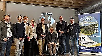 Gruppe von acht Menschen posiert vor einer Leinwand mit der Aufschrift "Nachhaltigkeit Ausstellung". Rechts ein Banner mit der Aufschrift "Euregio Inntal".